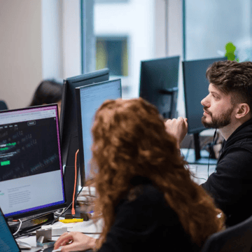 A woman and man - seen from the back - looking at computer screens
