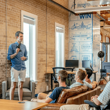 Person speaking at an event, others listening